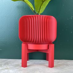 a red planter sitting on top of a wooden stand next to a green wall