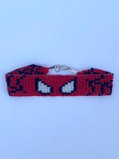 red and black beaded bracelet with white eyes on the front, one eye closed