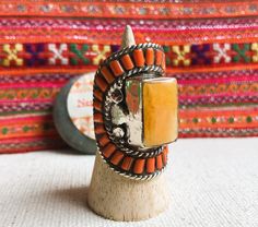 This is a Magnificent Tibetan ethnic ring, it was designed on a model of old traditional Tibetan jewelry. It is entirely handmade. This is a rare piece (limited quantity). It is made of Tibetan silver inlaid with coral and amber resin. It is very bright. This is a very large ring. Length of the ring: 4.2 cm Width of the ring: 2.5 cm Ring weight: 34 grams Does not contain nickel, lead or cadmium. It will be shipped in a small pouch. Shipping will be fast and careful. Visit the NEPALMASHOP.FR stor Traditional Gemstone Rings For Collectors, Artisan Carved Adjustable Ring, Artisan Carved Rings, Traditional Carved Rings For Ceremonial Occasions, Traditional Carved Ceremonial Rings, Traditional Orange Gemstone Jewelry, Bohemian Carved Ring Jewelry, Handmade Bohemian Orange Ring, Bohemian Handmade Collectible Rings