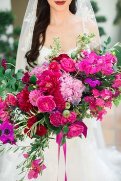 a bride holding a bouquet of pink and red flowers