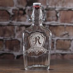 a glass bottle sitting on top of a wooden table next to a brick wall in the background