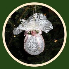 an ornament hanging from a christmas tree decorated with white lace and pink flowers