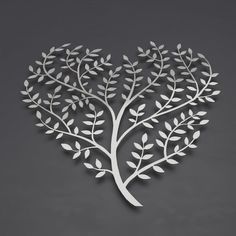 a metal heart shaped tree with leaves and branches on the side, cut out from white paper