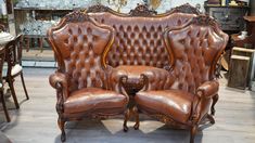 two brown leather chairs sitting next to each other