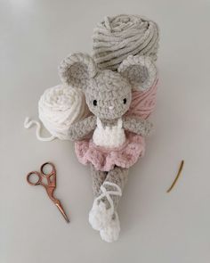 a crocheted mouse sitting on top of a table next to yarn and scissors