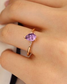 a woman's hand with a gold ring and an amethoraite stone