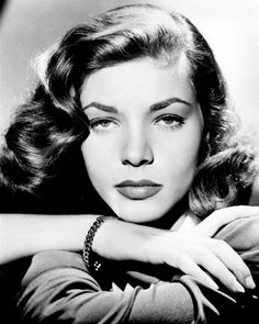 a black and white photo of a woman with her hands on her knees, leaning against the wall