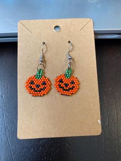 a pair of beaded pumpkin earrings sitting on top of a table