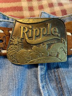 These vintage Ripple Wines belt buckles have lettering and fruits on the front.  The back has a hook and bar for a snap on belt.  Fits up to a 1 3/4" wide belt.  These are original stock from the 1970's.  They have gotten a dark patina due to age. $20 each. Sales final, as is, no returns. Vintage Belt Buckles, Vintage Belt, A Hook, Suspender Belt, Wide Belt, Dallas Tx, Belt Buckle, Suspenders, Belt Buckles