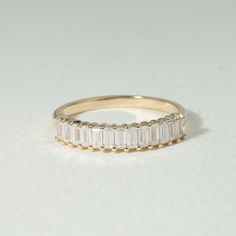 a yellow gold ring with baguettes on the side, set against a white background