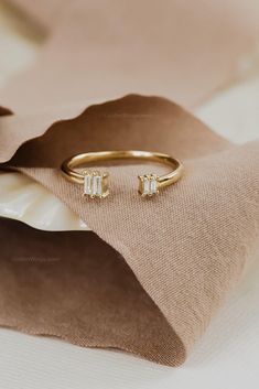 a close up of a gold ring with two stones on it and a beige cloth