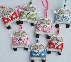 four felt ornaments with the vw bus design on them are hanging from strings and decorated with beads