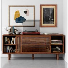 a record player sitting on top of a wooden cabinet in front of two framed pictures