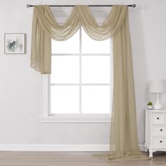 a white room with a large window and beige drapes on the windowsills