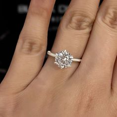 a woman's hand with a diamond ring on top of her finger and an engagement band