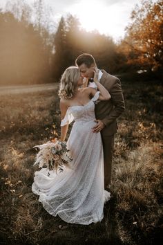 a bride and groom are standing in the grass