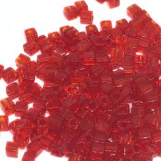 red glass beads are scattered on a white surface