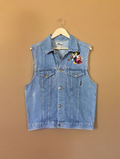 "Awesome 90's Mickey Mouse denim vest. Vest is in great & clean condition with little signs of previous wear. Perfectly worn in with naturally distressed denim character. Traditional Mickey Mouse embroidered emblems on front and back. Embroidery in great shape. Full button up front with adjustable buttons in back. Lightweight denim 100% cotton. See photos for details. Measurements (taken zipped-buttoned up and laid comfortably flat) x2 for total circumference (inches) Size Medium Shoulders 1 90s Style Spring Denim Jacket, Casual Festival Vest With Pockets, Casual Denim Festival Vest, Casual Denim Vest For Festivals, 90s Cotton Denim Vest With Pockets, 90s Style Cotton Denim Vest With Pockets, Retro Cotton Denim Vest For Spring, Vintage Denim Vest For Festival, 90s Style Medium Wash Denim Vest For Spring