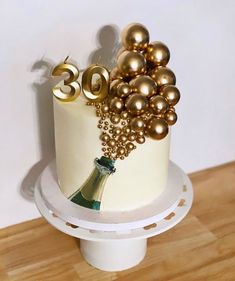 a white cake with gold decorations and a wine bottle on the top that says 30th