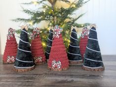 small christmas trees with bows on them sitting in front of a christmas tree