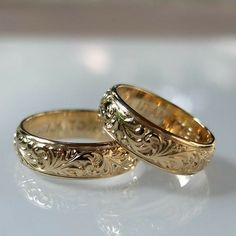 two gold wedding rings sitting next to each other