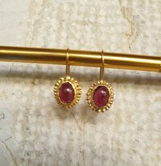 14k gold earrings, Garnet earrings, January birthstone earrings, Antique inspired earrings, vintage earrings, Red oval earrings These antique inspired red Garnet earrings were 100% handmade. The see through wine red Garnet stones are just beautiful and shine softly against the gold contour of the earrings. These January Birthstone earrings are just the perfect gift for yourself or someone you love. They can be great gold bridal earrings. Dimensions: The earrings drop length is 2.5cm or 1 inch Th Vintage Gold Gemstone Earrings, Elegant Gold Garnet Cabochon Jewelry, Heirloom Oval Gold Earrings, Gold Brass Earrings With Cabochon Detail, Gold Cabochon Brass Earrings, Gold Brass Cabochon Earrings, Heirloom 14k Gold Oval Earrings, Heirloom Oval 14k Gold Earrings, Gold Garnet Earrings As Gift