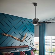 a bed room with a neatly made bed and a ceiling fan in the middle of it