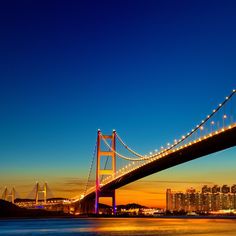 the bay bridge is lit up at night with bright lights on it's sides