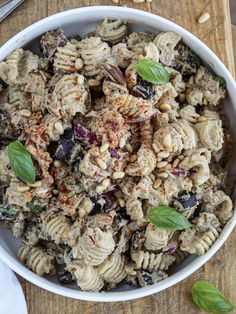 a white bowl filled with pasta salad on top of a wooden cutting board