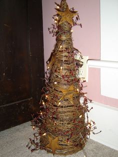 a christmas tree made out of straw with red berries on the bottom and gold star decorations