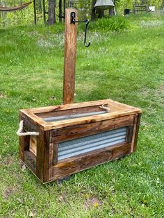 a wooden box sitting on top of a grass covered field next to a metal object