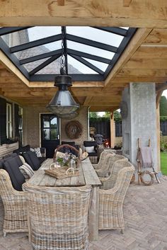 an outdoor dining area with wicker furniture and a glass roof over the fire pit