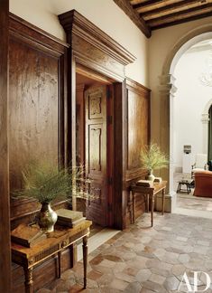 an entry way with wooden doors and two vases on a table in front of it