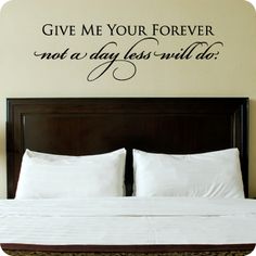 a bed with white sheets and pillows in front of a wall decal that says give me your forever not a day less until do