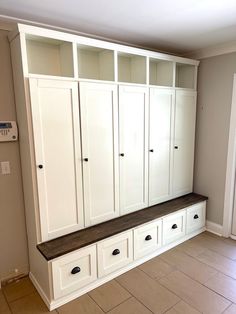 an empty room with some white cabinets and drawers on the wall, in front of a tile floor