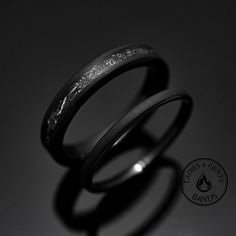 two black rings sitting next to each other on top of a table in front of a dark background