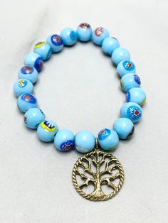 Vintage Blue Glass Mosaic Beaded Charm Bracelet. Gold tone charm of tree of life. Blue glass beads with mosaic flowers. Stretch bracelet.   JH33. Blue Bohemian Glass Bracelets, Bohemian Blue Glass Bracelets, Bohemian Light Blue Beads For Gift, Bohemian Light Blue Beads For Gifts, Bohemian Light Blue Beads As Gift, Nickel-free Blue Bohemian Beaded Bracelets, Nickel Free Blue Bohemian Beaded Bracelets, Nickel Free Bohemian Blue Beaded Bracelets, Blue Czech Glass Beaded Spiritual Bracelets