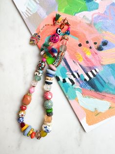 ABOUT THIS PIECE: "Carnival" necklace.  Handcrafted, one-of-a-kind, eco-friendly piece entailing: recycled glass, tiny cotton tassels, Swarovski Crystal, carved wood, handmade ceramic + paper beads, bamboo coral, seed bead and 14K gold vermeil hardware. 16" with a 2.5" extender.  Wear this statement necklace anywhere, be it a casual day with a white tee + jeans to a special occasion or on vacation.  Here are the other products in my shop:  www.etsy.com/ca/shop/RubyBlueCo I'm happy to custom make Whimsical Multicolor Jewelry With Charms, Whimsical Multicolor Charms Jewelry, Playful Multicolor Necklaces With Charms, Fun Multicolor Jewelry With Lobster Clasp, Beach Jewelry: Long Necklace With Large Beads, Party Multicolor Charms Necklaces, Whimsical Pendant Charm Necklace, Fun Multicolor Charm Jewelry, Long Beach Necklace With Large Beads