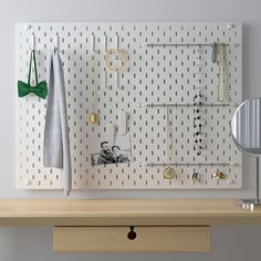 a white pegboard with several different items on it and a green bow tie hanging from the wall