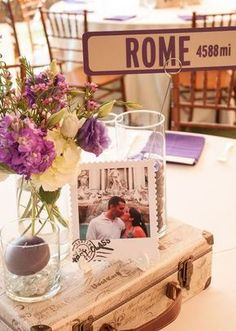 a table topped with a vase filled with purple and white flowers next to a sign that says rome