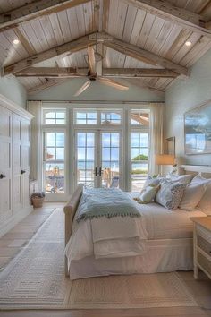 a large bed sitting under a wooden ceiling in a bedroom next to a window with sliding glass doors