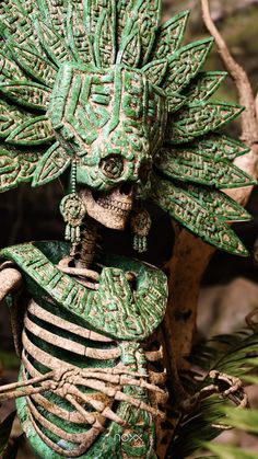 a green skeleton statue sitting next to a tree