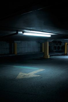 an empty parking garage with the light on and arrow painted on the ground in front of it