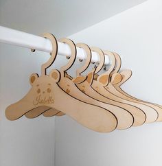 a row of wooden clothes hangers with personalized name on them hanging from a white wall