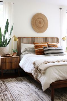 a bed room with a neatly made bed and a plant on the side table next to it