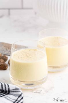 two glasses filled with pudding sitting on top of a counter next to nuts and a knife