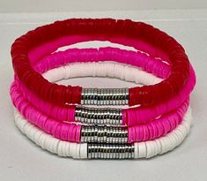 three different colored bracelets with metal clasps on white table top, one pink and the other red