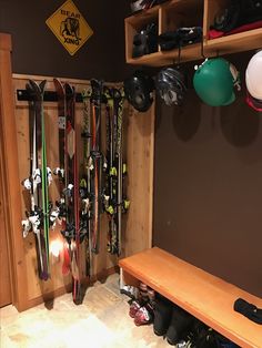 skis and snowboards are hanging on the wall in a room with wooden shelves