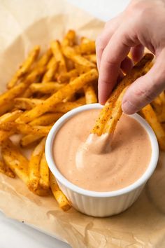 french fry sauce in a small white bowl with a hand dipping it into the dip