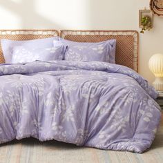 a bed with purple sheets and pillows in a room